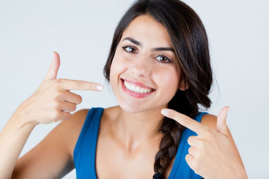 Woman Pointing To Her Smile After Full Mouth Reconstruction